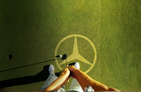 Golfrasen mit Mercedes-Benz Logo Golfrasen mit Mercedes-Benz Logo und Golfschläger, der Ball ins Loch spielt
